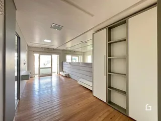 Corredor interno com piso de madeira e armários embutidos.