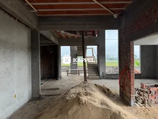 Foto de uma estrutura em construção com vigas de concreto e paredes de tijolo expostas.