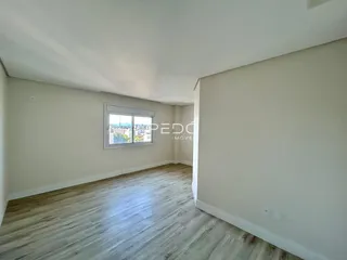 Ambiente interno de uma sala com piso de madeira clara e janela.