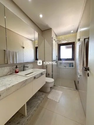 Banheiro moderno com bancada de mármore e box de vidro.