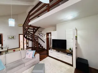 Sala de estar com escadaria de madeira e piso de madeira.