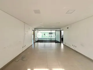 Um corredor longo e vazio com piso de cerâmica e paredes brancas.