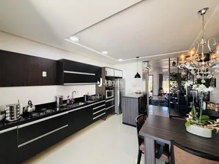 Vista da cozinha moderna com armários escuros e bancadas escuras.