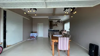 Uma sala de jantar com mesa de madeira e iluminação pendente.