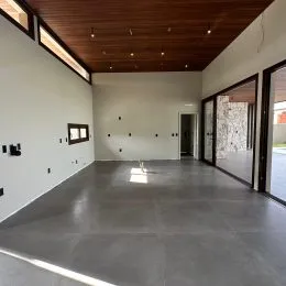 Espaço interno amplo com piso de concreto polido e forro de madeira.