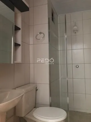 Foto de um banheiro com revestimento cerâmico e box de vidro.