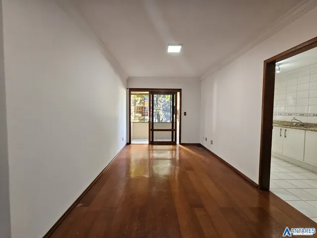 Hall de corredor com piso de madeira e paredes brancas.