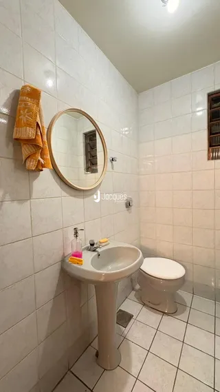Banheiro com azulejos brancos e louças sanitárias.