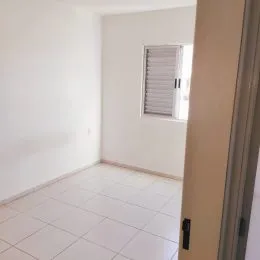 Vista interna de um cômodo com piso de cerâmica branca e paredes brancas.