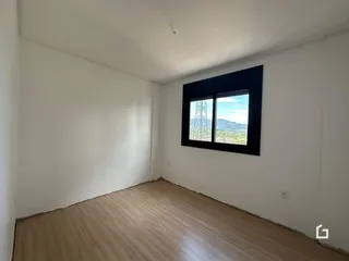 Ambiente interno de uma sala com piso de madeira clara e janela com vista para a paisagem.