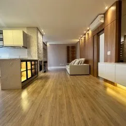 Sala de estar com piso de madeira clara e painéis de madeira.
