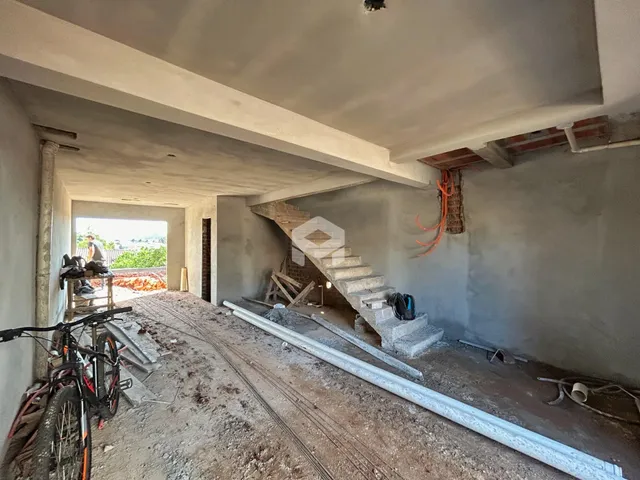 Vista interna de uma área em construção com estrutura de concreto aparente.