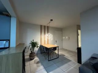 Sala de jantar com mesa de madeira e piso de cerâmica em um apartamento.