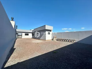Vista externa de uma residência moderna com parede branca e área de terra em Lajeado, Brasil.