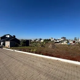 Vista externa da propriedade mostrando paisagem com vegetação e área pavimentada.