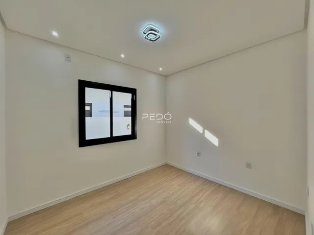 Ambiente interno de uma sala com piso de madeira clara e paredes brancas.
