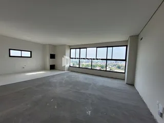 Ambiente interno com paredes brancas e grande janela de vista para a cidade.