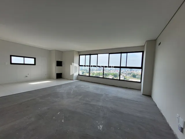 Ambiente interno com paredes brancas e grande janela de vista para a cidade.