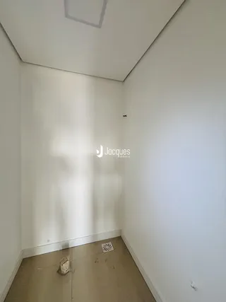 Vista interna de um cômodo com paredes brancas e teto inclinado.
