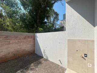 Fachada de uma propriedade em Lajeado, Brasil, com muro de tijolos e reboco branco.
