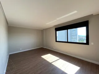 Sala de estar com piso de madeira e grande janela com vista para a cidade.