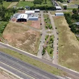 Vista aérea de uma propriedade com campos ao redor e uma estrada.