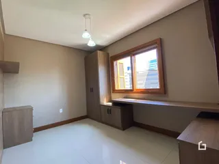 Ambiente interno de uma sala com piso de cerâmica clara e molduras de madeira.