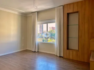 Sala de estar com piso de madeira e janela grande.
