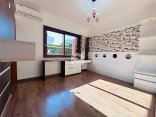 Sala de estar com piso de madeira e grande janela em um imóvel no Brasil.
