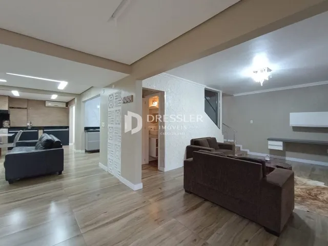 Sala de estar com piso de madeira clara e sofá marrom no interior de uma residência.