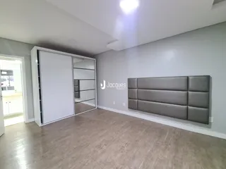 Ambiente interno com piso de madeira e armários embutidos em cinza claro.