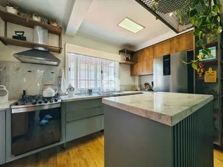 Cozinha moderna com armários em tons de verde e bancadas de mármore.