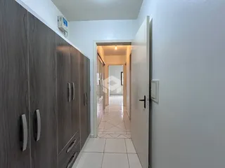 Vista de um corredor interno com armário e piso de cerâmica.