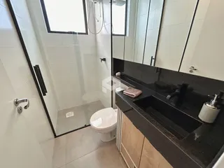 Foto de um banheiro moderno com box de vidro e bancada escura.
