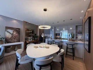 Uma sala de jantar moderna com mesa redonda e iluminação suspensa.