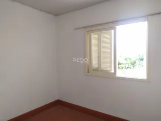 Parede branca e piso de madeira de um cômodo interno.