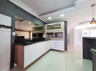 Vista da cozinha moderna com armários brancos e bancadas escuras.