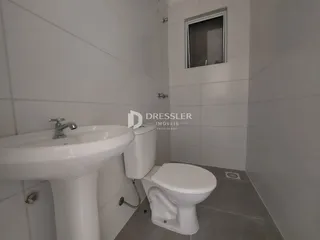 Foto interna de um banheiro com pia e vaso sanitário em cerâmica branca.
