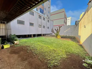 Vista externa de um terreno com gramado e muro lateral.