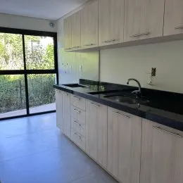 Foto de uma cozinha com armários brancos e bancada escura.