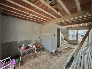 Imagem de um cômodo interno em construção com teto de madeira exposto.