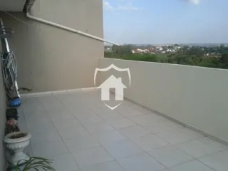 Área externa pavimentada com parede branca e grade.