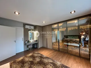 Quarto com piso de madeira e portas de vidro no interior de uma residência.