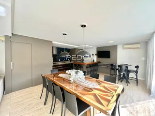 Uma sala de jantar ampla com mesa de madeira no interior de uma residência.