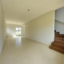 Uma foto de um corredor interno com paredes brancas e piso claro.