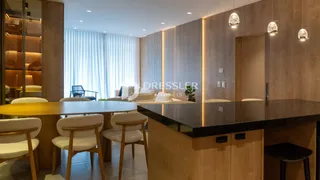 Interior de uma sala de estar com painéis de madeira e grandes janelas.