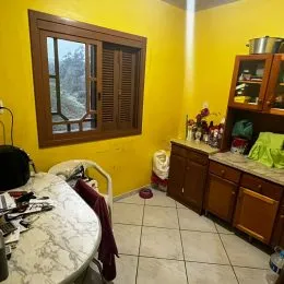 Sala de estar com paredes amarelas e janela de madeira.