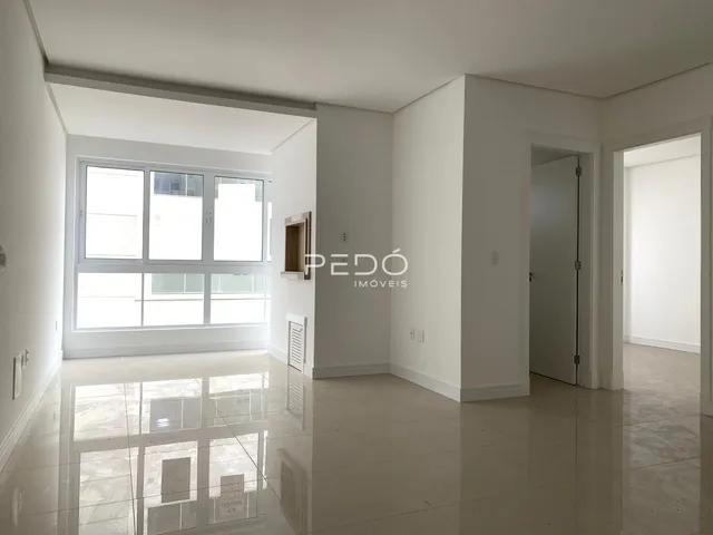 Interior de uma sala ampla com piso reflexivo e grande janela.