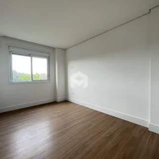 Vista interna de uma sala com piso de madeira clara e paredes brancas.