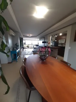 Vista interna de uma sala de jantar com mesa de madeira.